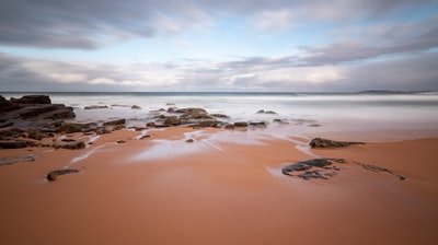 Brown sand near water during the day
